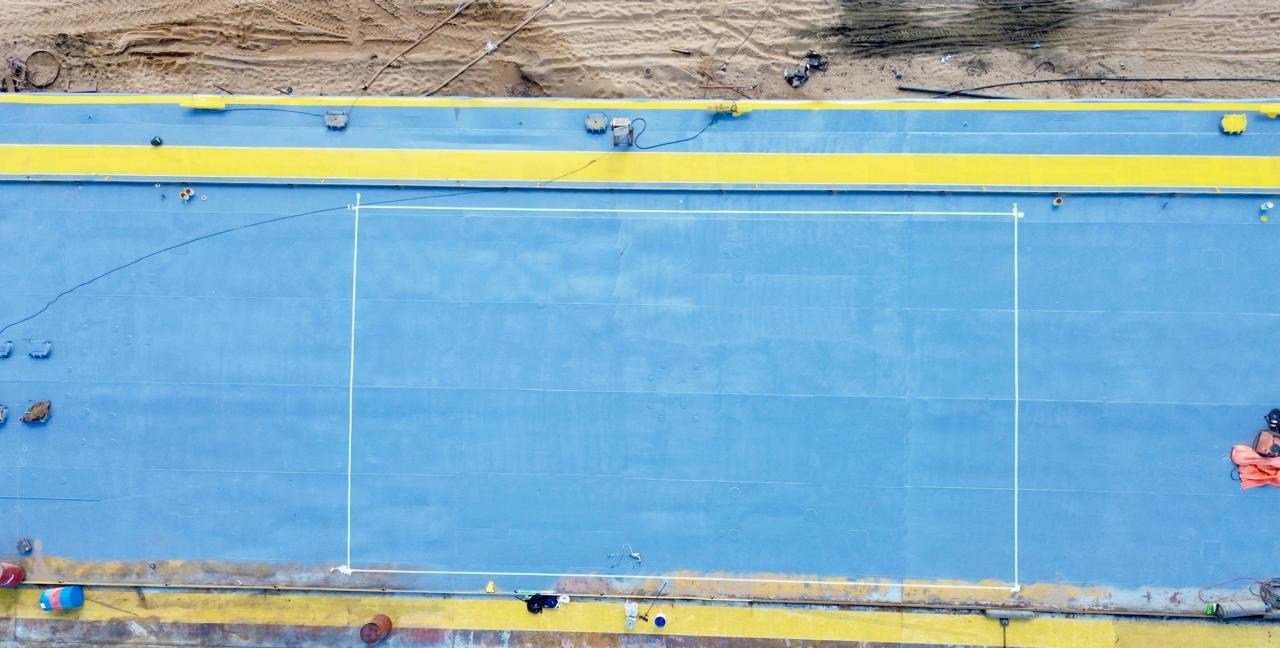 Vista aérea de la cubierta de una barcaza pintada en azul con bordes amarillos