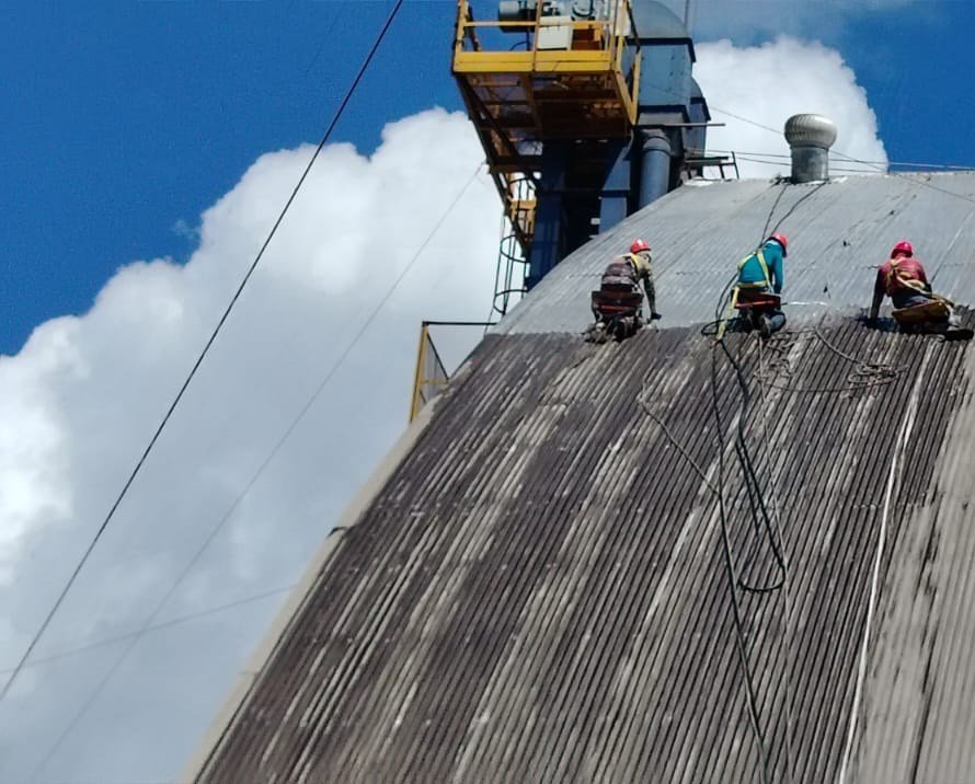 Operarios trabajando sobre el techo curvo de una nave industrial